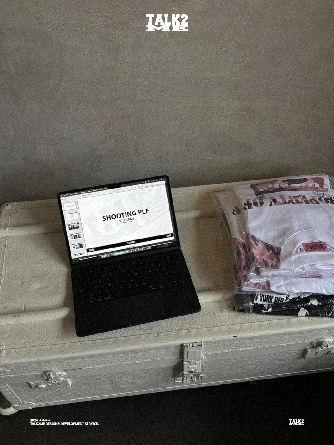 Content-Talks Behind the Scenes: Laptop mit Shooting-Ablauf neben gefalteten Shirts.