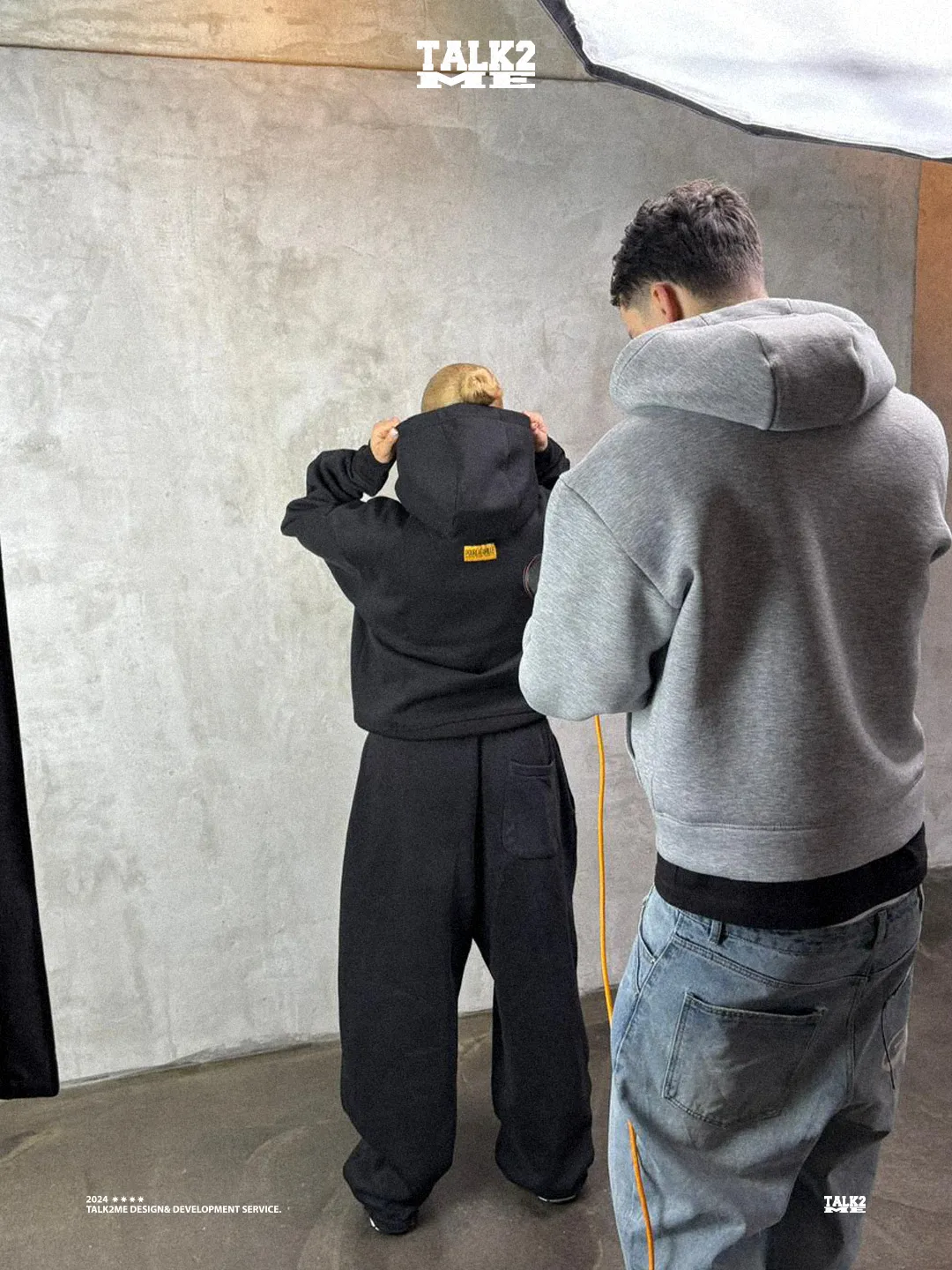 Content-Talks Behind the Scenes: Model und Fotograf richten im Studio einen schwarzen Hoodie.