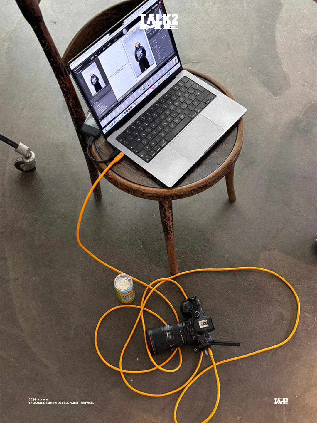 Content-Talks Behind the Scenes: MacBook per orangefarbenem Kabel mit der Kamera getethert auf einem Holzstuhl.
