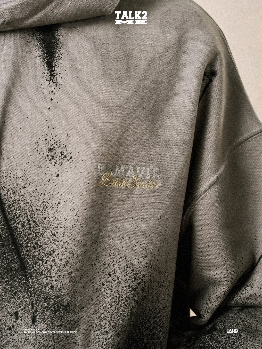 Content-Talks-Editorial: grauer Hoodie mit La-Vie-Stickerei und Farbspray-Details.