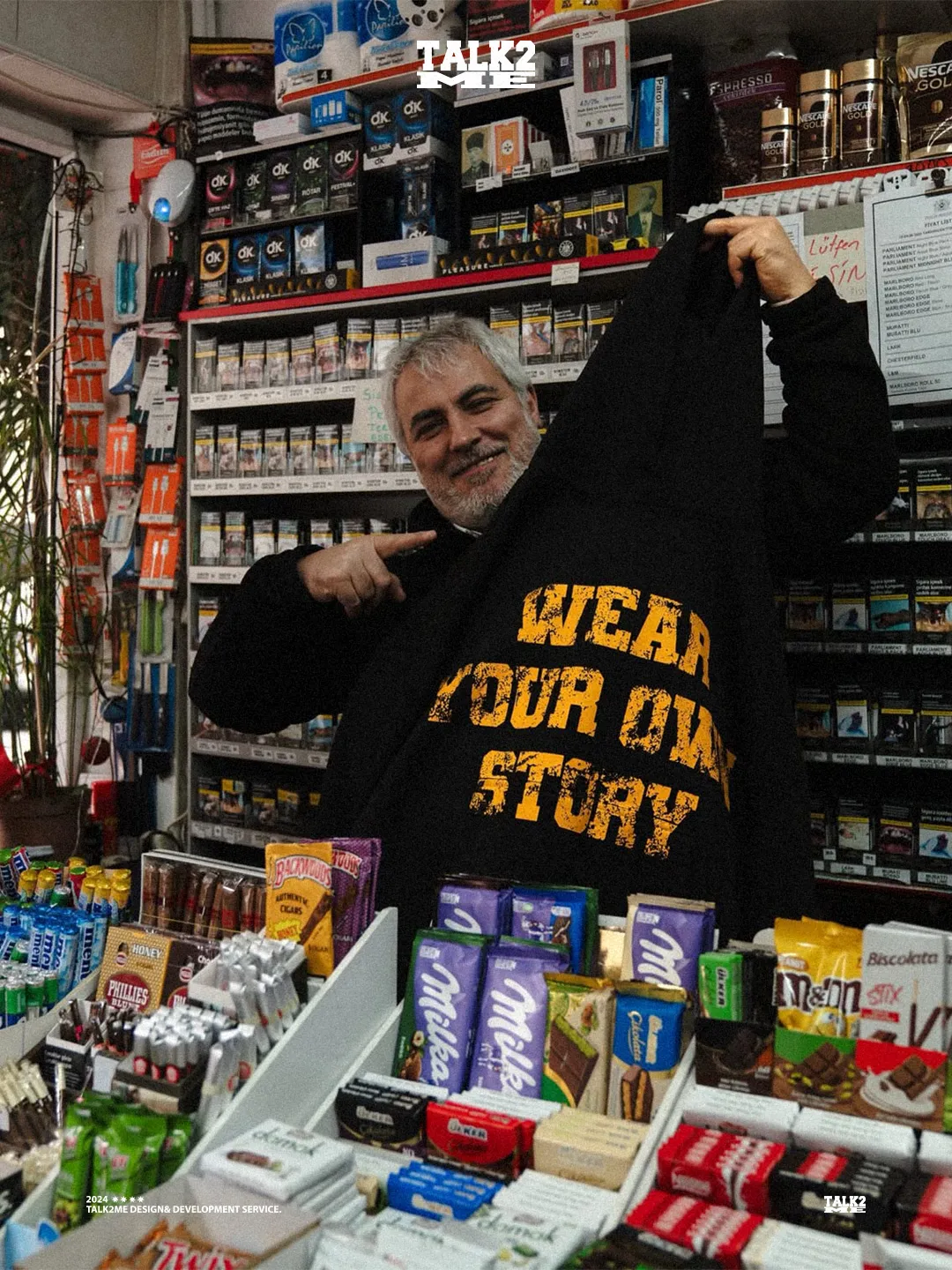 Content-Talks-Story Wear Your Own Story: Mann in einem Kiosk hält einen Hoodie.